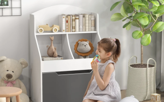 Little girl sitting near white and gray kids bookcase with books, toys, and decor in a cozy playroom setting.