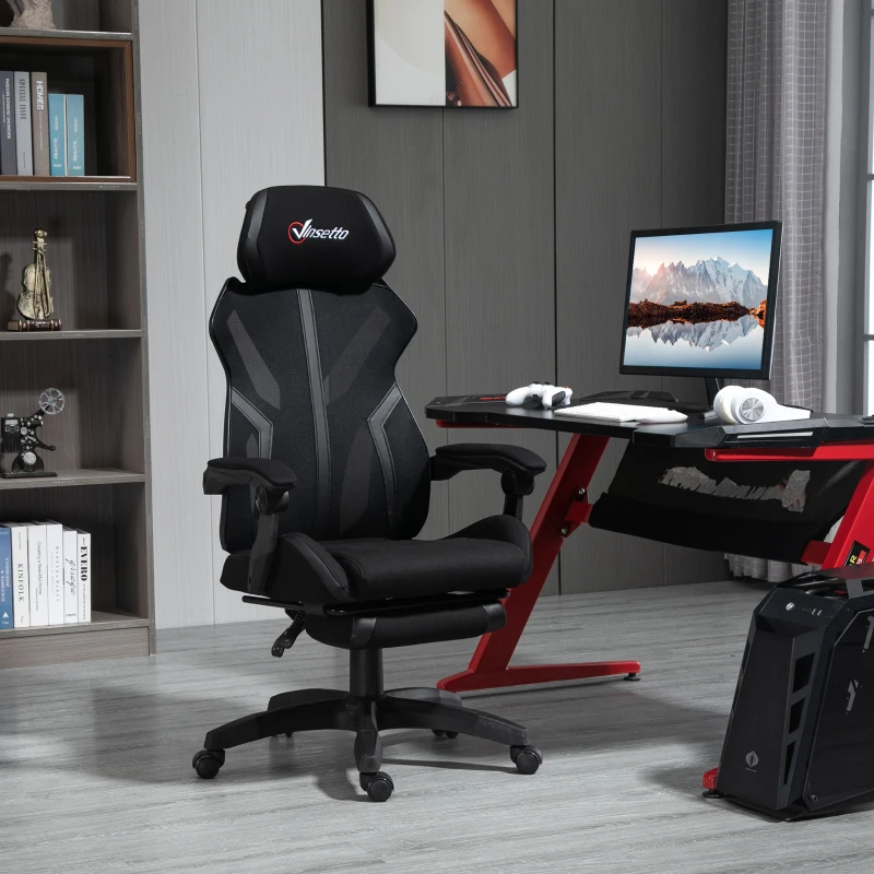 Black ergonomic gaming chair with headrest beside red-accented desk