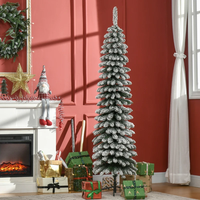 Tall snow-flocked pencil Christmas tree with gifts and red wall backdrop.
