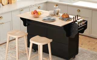 Light wood island centered in bright kitchen with matching cabinetry and pendant lights.