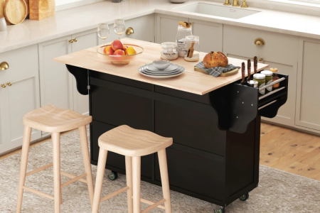 Light wood island centered in bright kitchen with matching cabinetry and pendant lights.