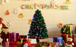 Decorated pre-lit Christmas tree glowing with colorful lights and holiday gifts underneath.