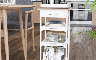 White-painted kitchen cart styled with plates, jars, and bottles in a modern kitchen.