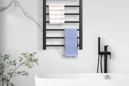Modern black towel warmer mounted on marble wall above bathtub.