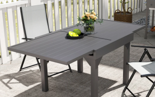 Modern gray extendable outdoor dining table set up on patio with chairs.