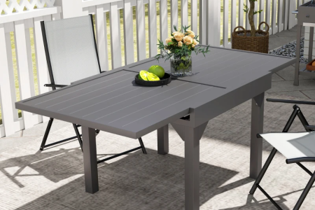 Modern gray extendable outdoor dining table set up on patio with chairs.