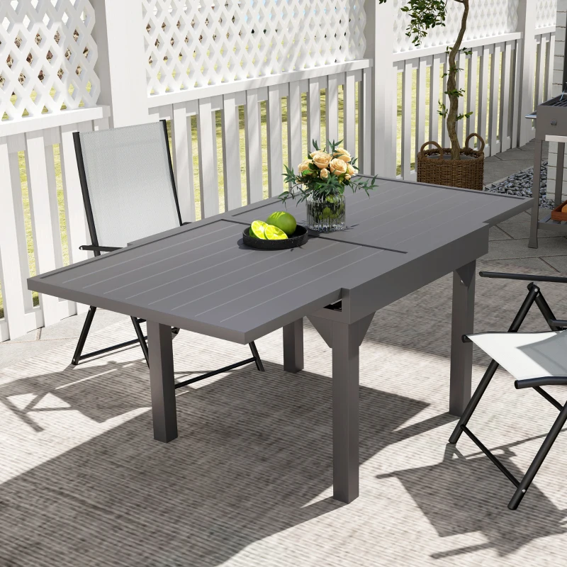 Modern gray extendable outdoor dining table set up on patio with chairs.