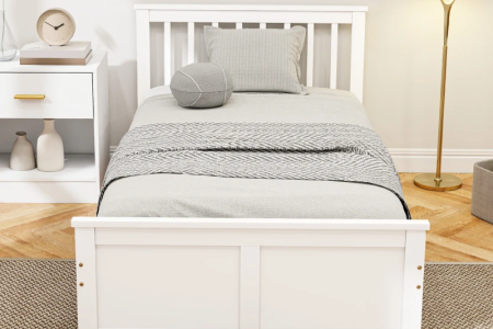 Modern twin bed with layered bedding, neutral tones, and cozy morning light.