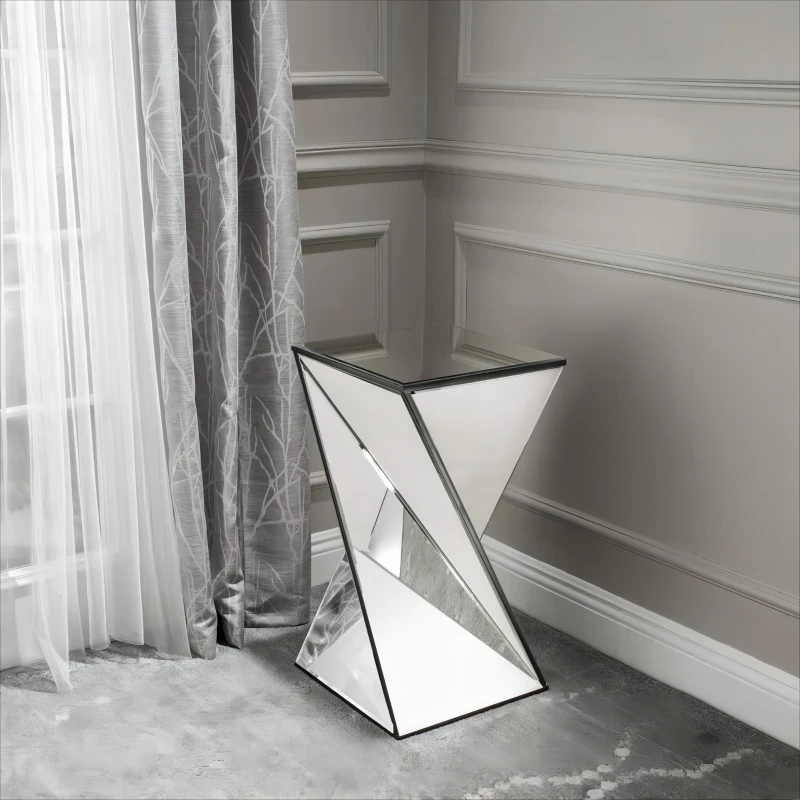 Modern mirrored accent table with geometric design reflecting natural light in grey room.