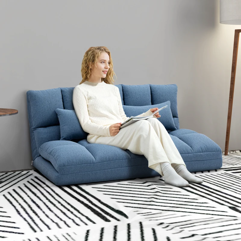 Woman relaxing on foldable blue floor sofa with soft cushions in cozy living space.