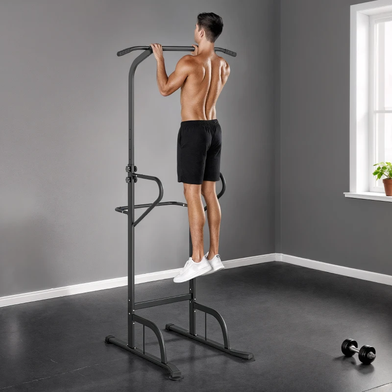 Man doing pull-ups on power tower dip station in gray room.