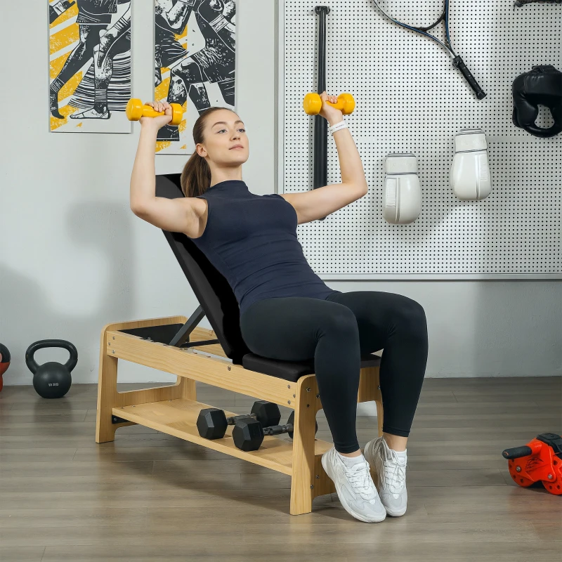 Woman lifting dumbbells on wooden adjustable weight bench in gym.