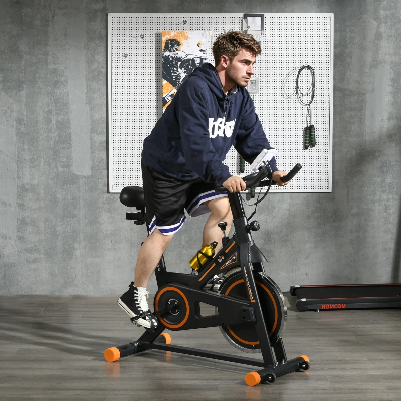 Man riding upright stationary exercise bike in home gym setup.
