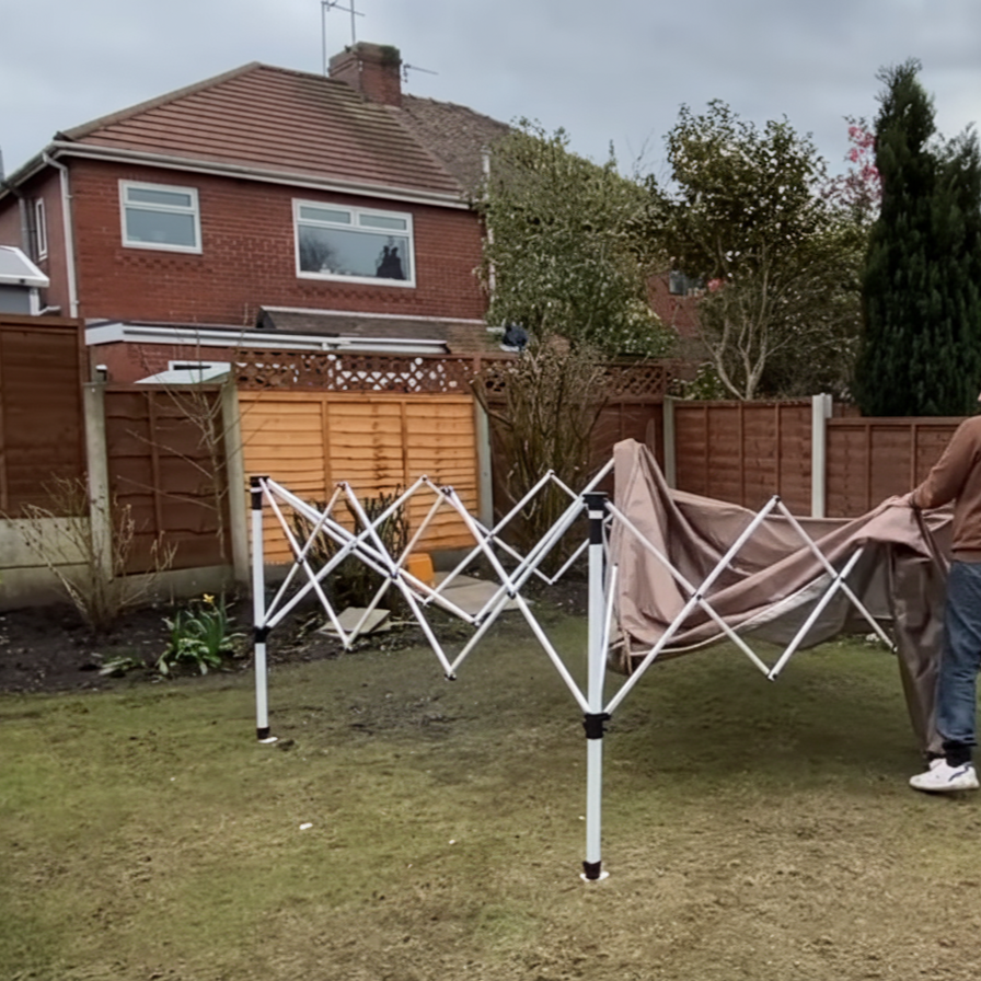 Person attaching brown canopy fabric to pop-up tent frame.