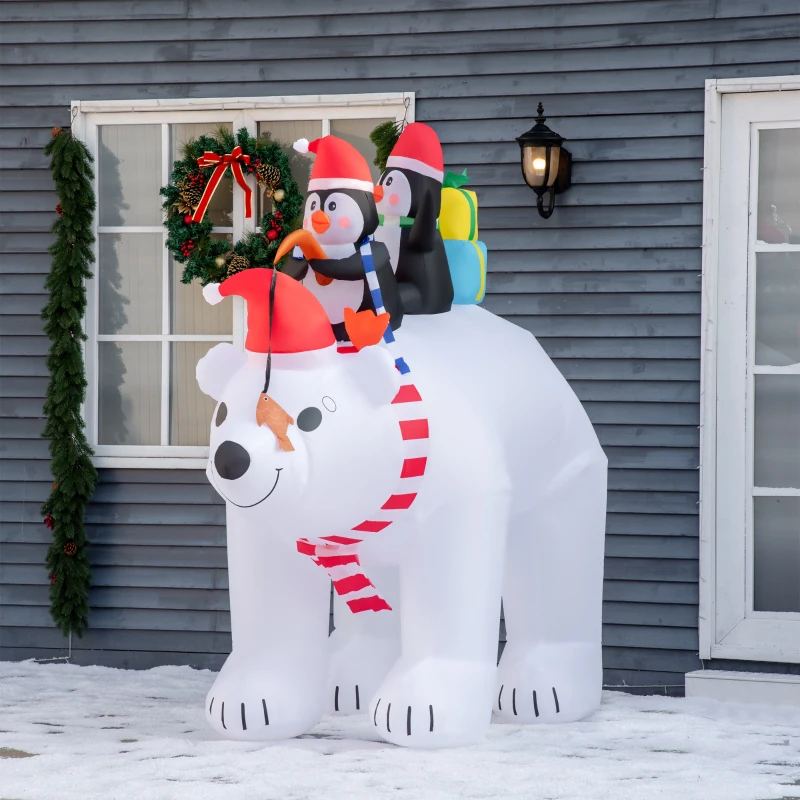 Inflatable polar bear with penguins in Santa hats in snowy yard.