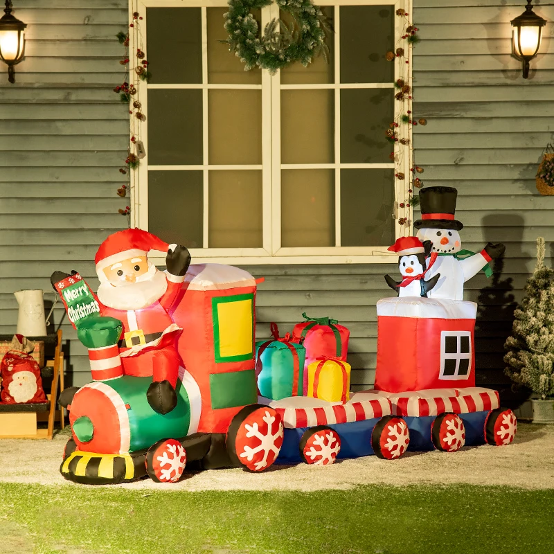 Inflatable Santa train with gifts and snowman outside festive home.