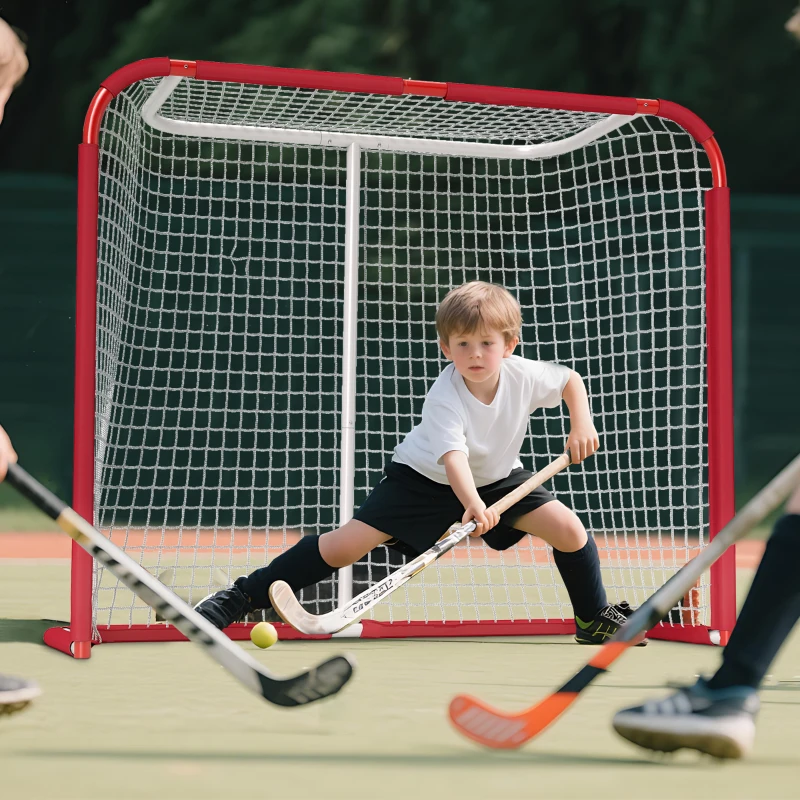 Young goalie defending hockey net during field hockey practice.