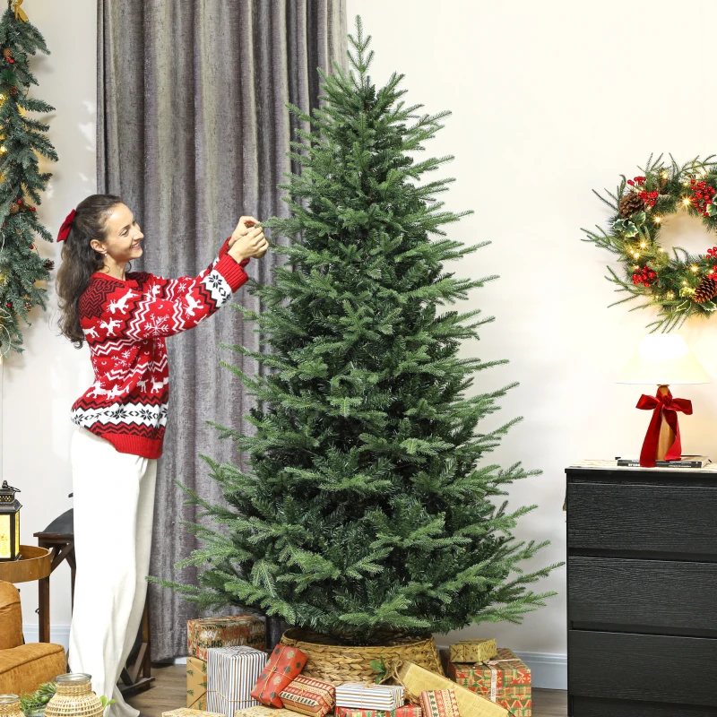 Smiling woman decorating tall Christmas tree beside wrapped gifts.