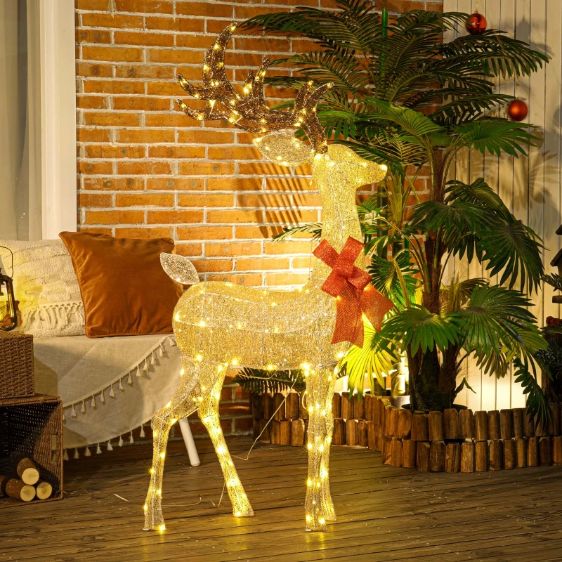 Illuminated golden reindeer decoration glowing on outdoor patio at night.