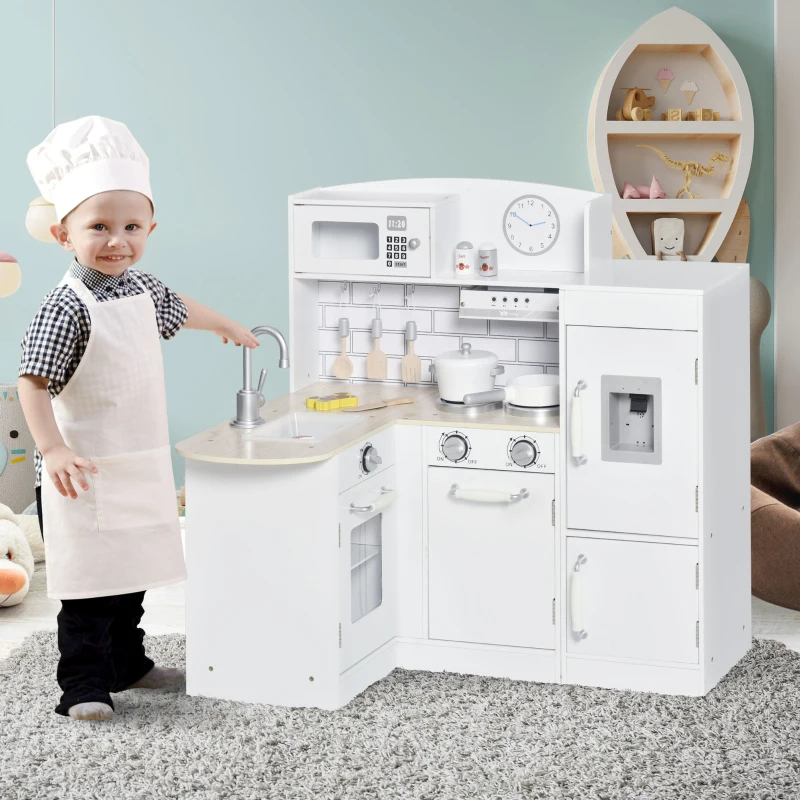 Smiling child in chef hat playing with white corner kitchen playset.