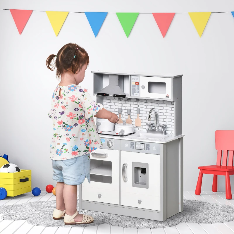 Toddler cooking on gray toy kitchen under colorful bunting in playroom.