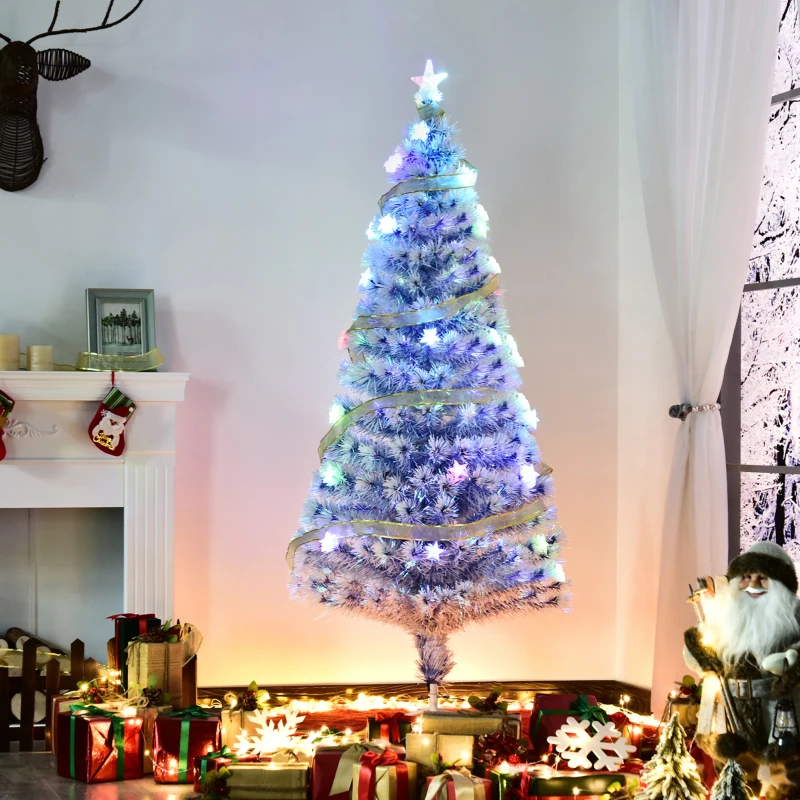 White pre-lit Christmas tree with glowing LED lights and ribbon standing near fireplace décor