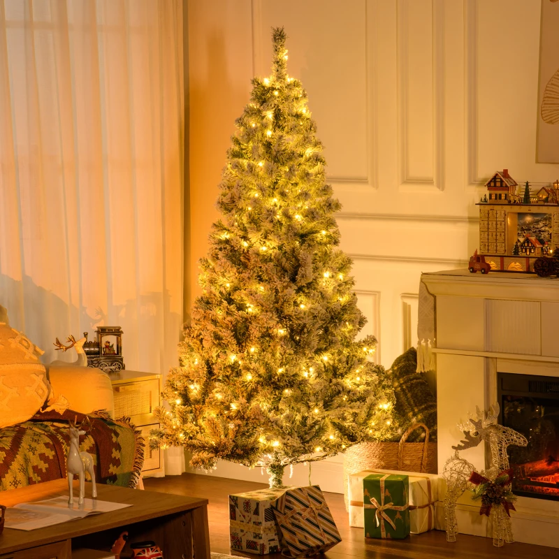 Snow-flocked pre-lit Christmas tree glowing warmly beside a cozy living room fireplace