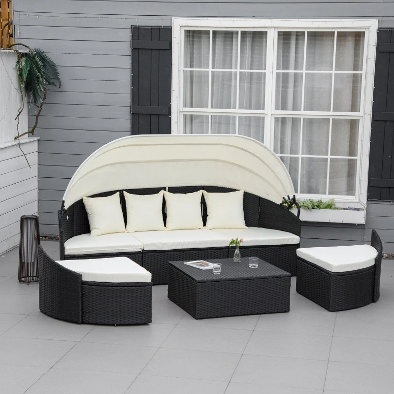 Black wicker sectional daybed with cream canopy and matching ottomans.