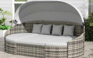Outdoor rattan daybed with canopy and gray cushions on patio.