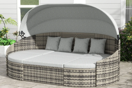 Outdoor rattan daybed with canopy and gray cushions on patio.