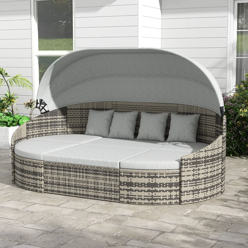Outdoor rattan daybed with canopy and gray cushions on patio.