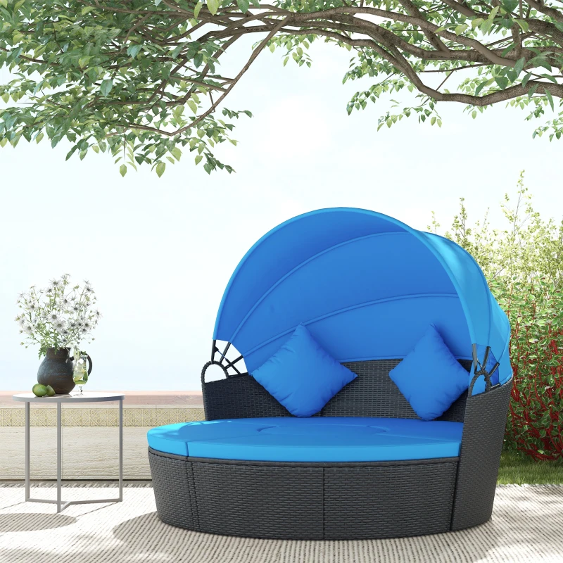 Rattan daybed with bright blue cushions beneath a tree on patio.