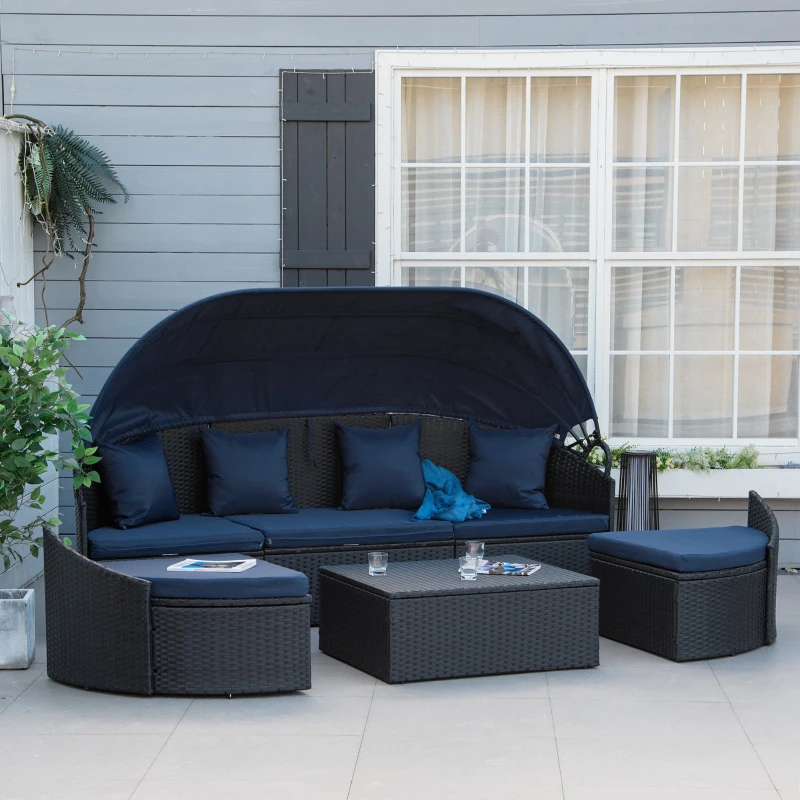 Black rattan daybed with cream cushions and canopy by the poolside.