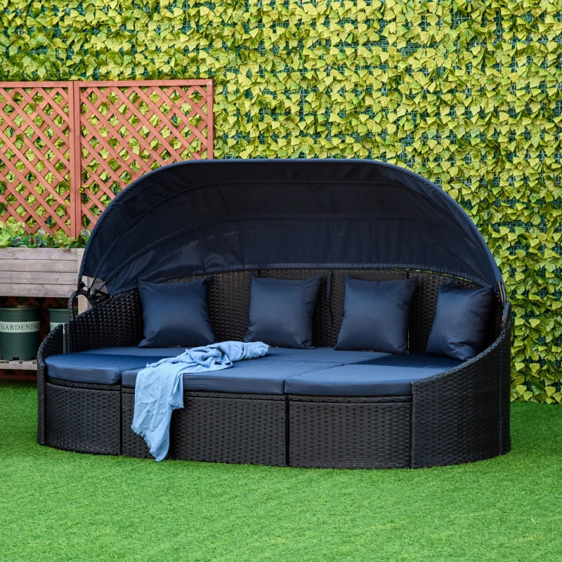 Rattan daybed with cream cushions and accent pillows in garden setting.