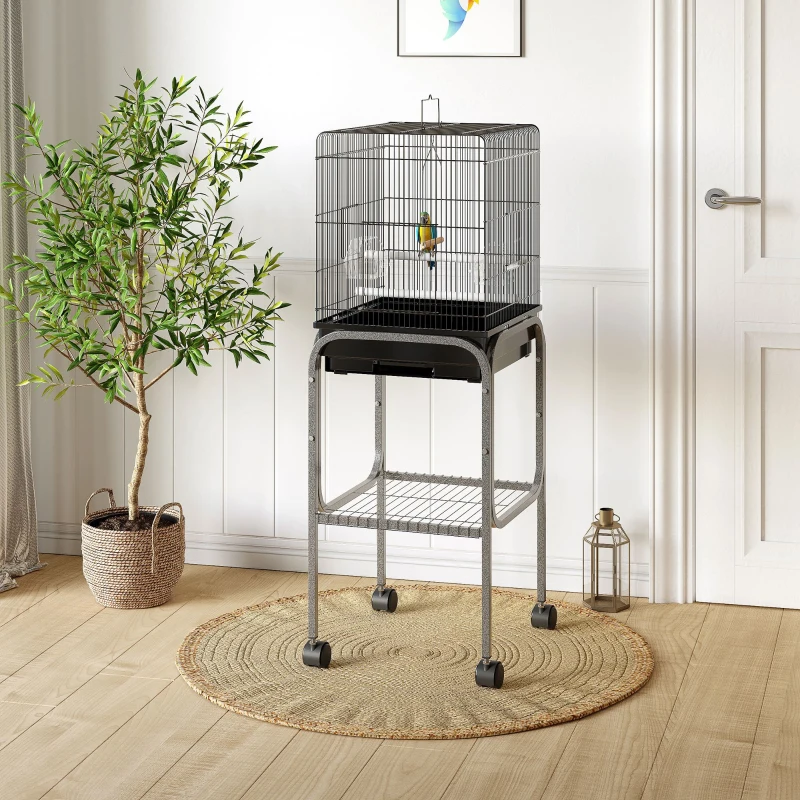 Single black bird cage with rolling stand in bright room beside potted plant.