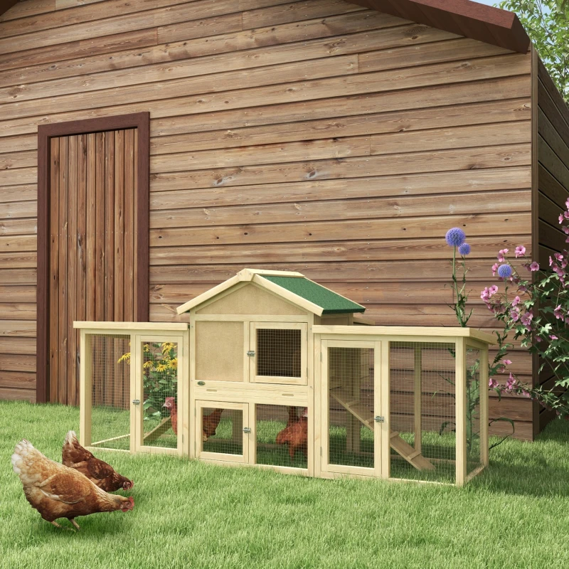 Wooden chicken coop with green roof, nesting box, and ramp beside a wooden barn.