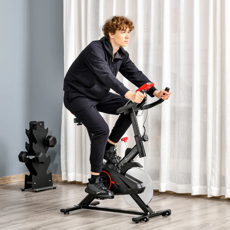 man riding black and red stationary exercise bike at home.