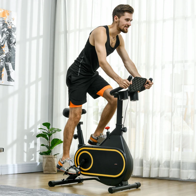 man cycling on black and yellow stationary bike indoors.