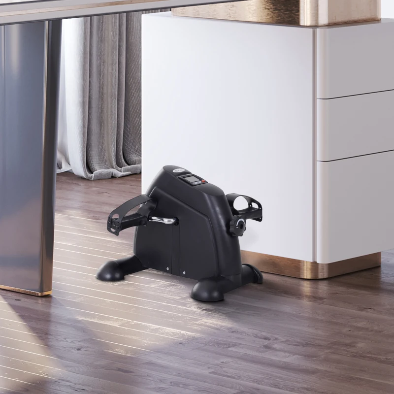 compact black under-desk pedal exerciser in home office.