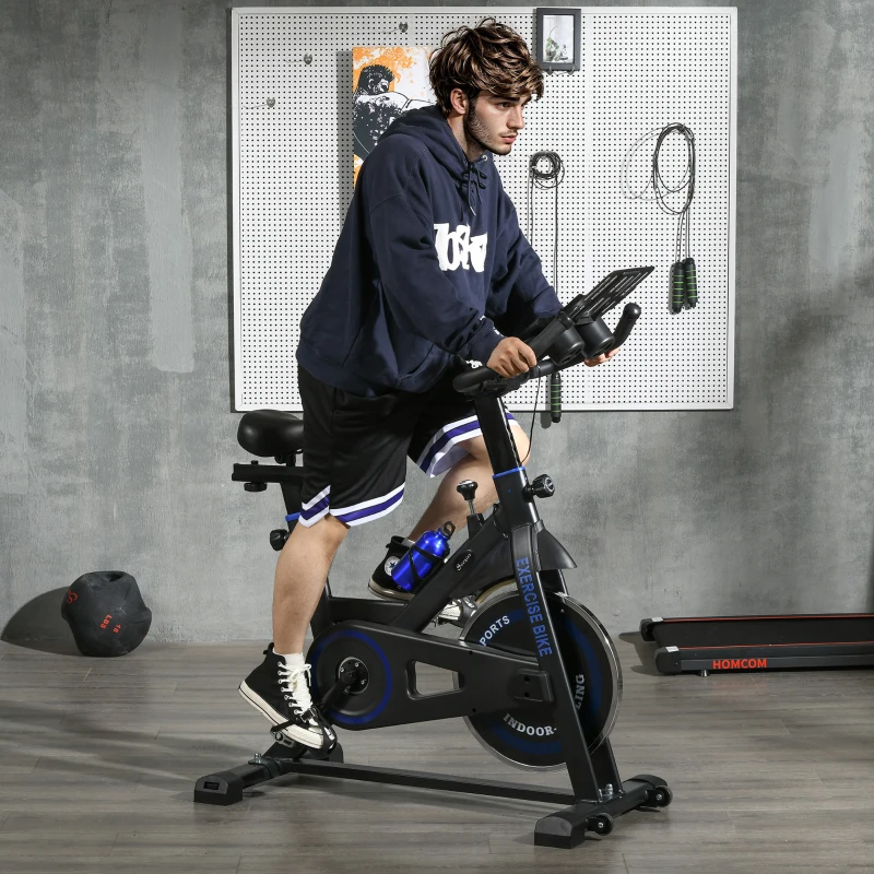 man training on black and blue indoor bike in home gym.