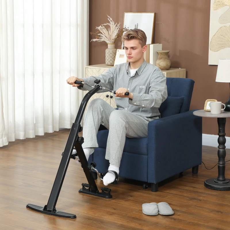 man using black seated pedal trainer while sitting on chair.