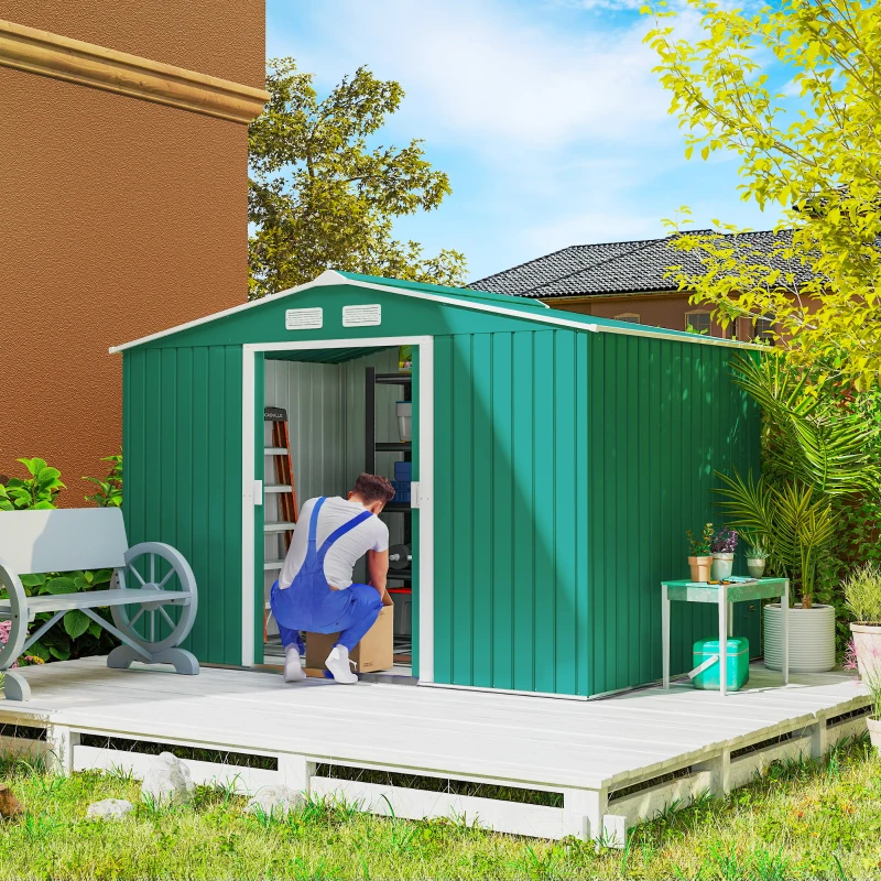 Green outdoor metal garden shed with bicycle and tools stored inside on a sunny patio.
