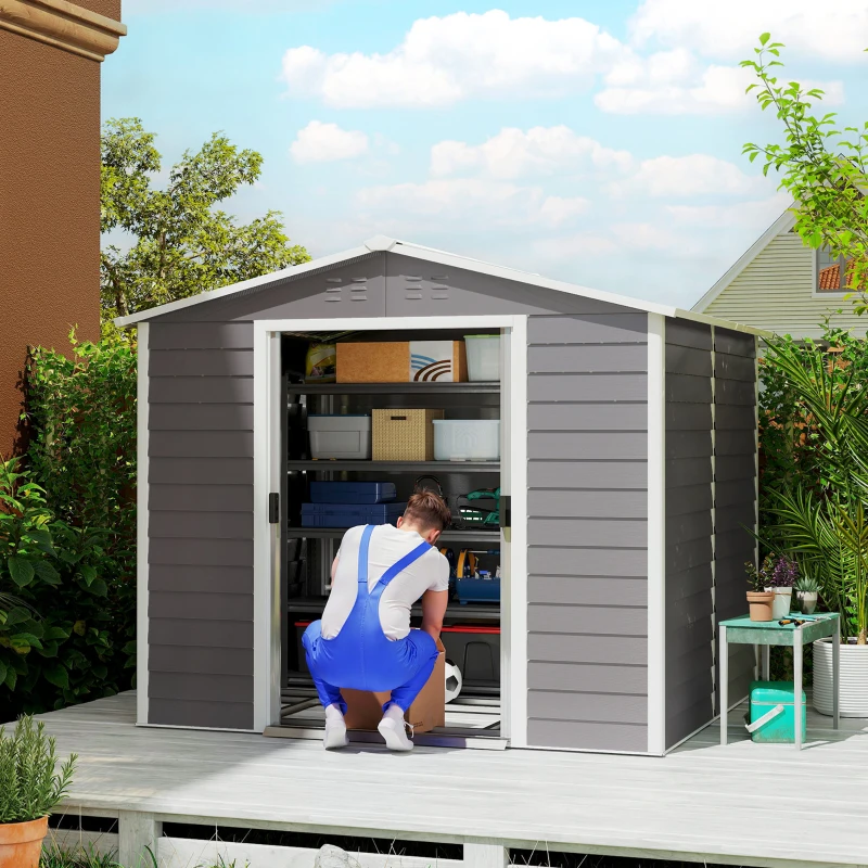 Grey metal shed with white trim, open doors showing man storing garden items inside.