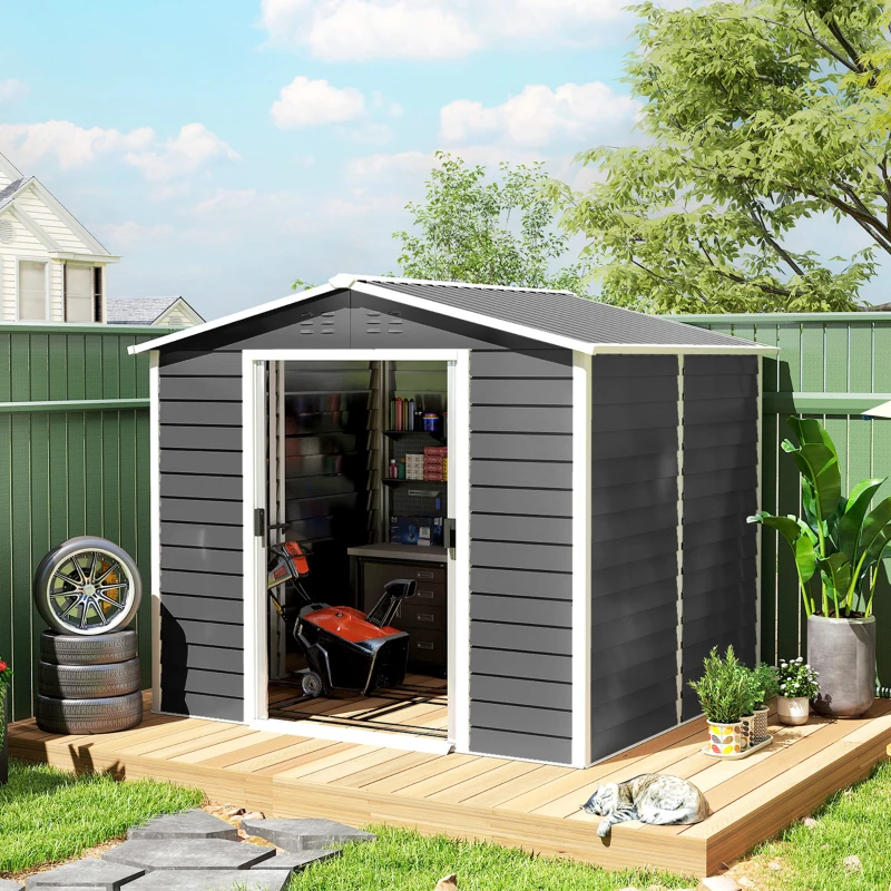 Large brown outdoor storage shed in sunny garden with plants and garden tools placed outside.