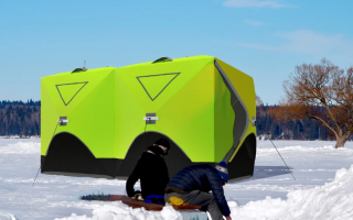 Bright green ice fishing tent on snowy lake with two people preparing gear.