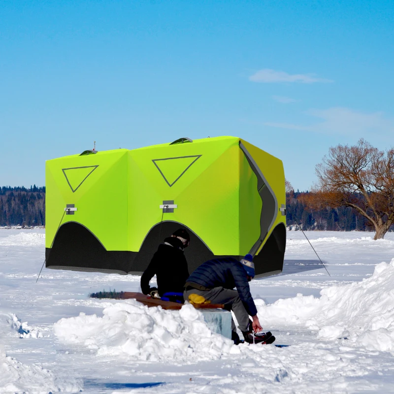 Bright green ice fishing tent on snowy lake with two people preparing gear.