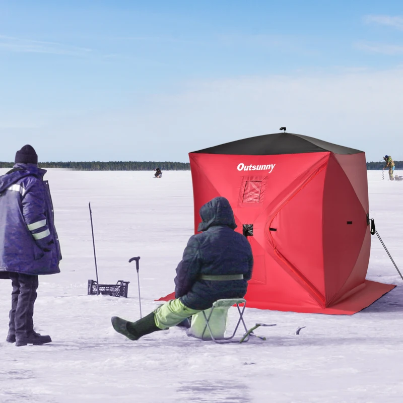 Red pop-up ice shelter on ice with people fishing nearby.