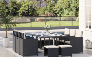 Modern black rattan patio dining set with cream cushions beside pool and garden view.