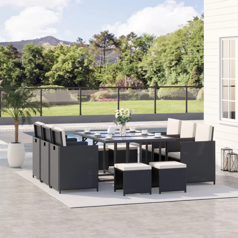 Modern black rattan patio dining set with cream cushions beside pool and garden view.