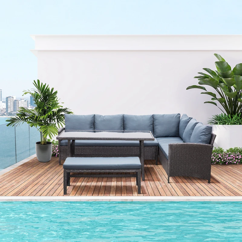 Grey rattan corner sofa set with bench beside rooftop pool and tropical plants.
